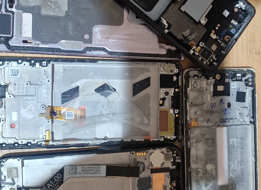 Razstavljeni telefoni z vidno notranjo elektroniko na naši delovni mizi